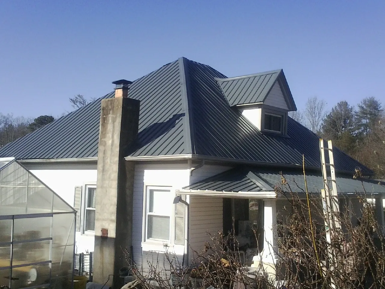 Dark blue standing seam metal roof on a white farmhouse with dormer — Slate & Tile Roof Repair by Roofing Brothers in Lupton City