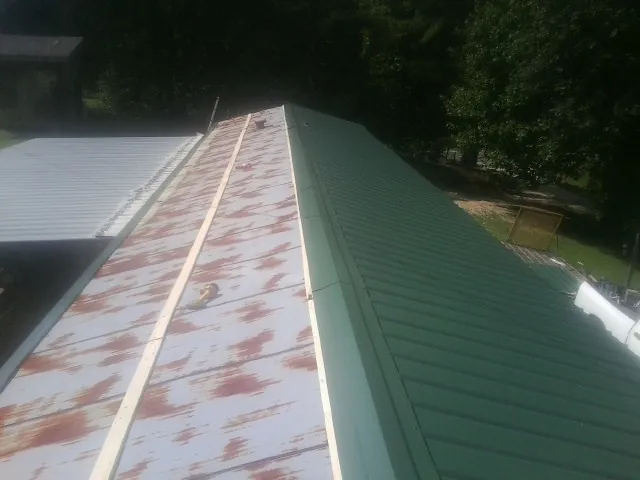 Old rusted panels beside newly installed green metal roofing — Wind Damage Roof Repair by Roofing Brothers in Lupton City