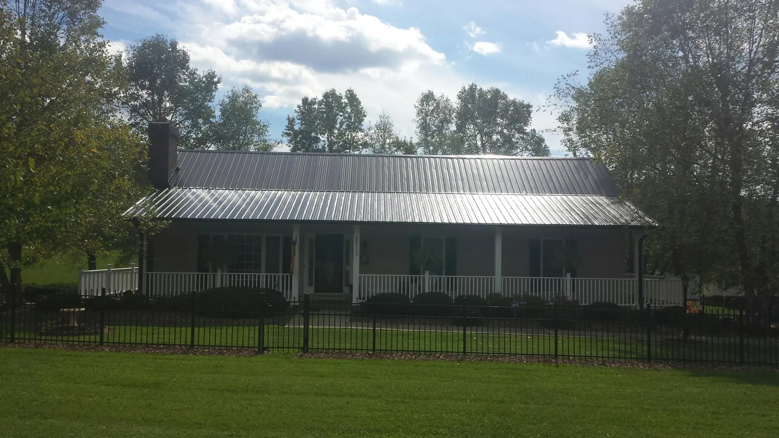 Gray metal roof on a brick ranch with a full width front porch — Gutter Guard Installation work by our crew in Lupton City