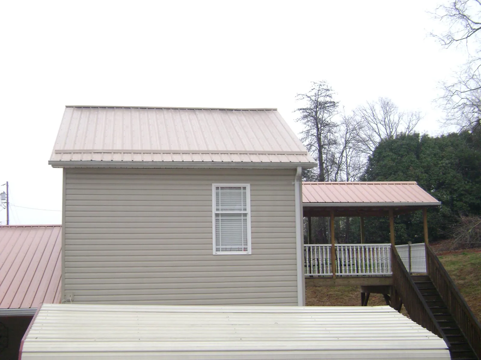 Tan metal roofs on a two story addition and attached porch, from a Roof Replacement job in Lupton City