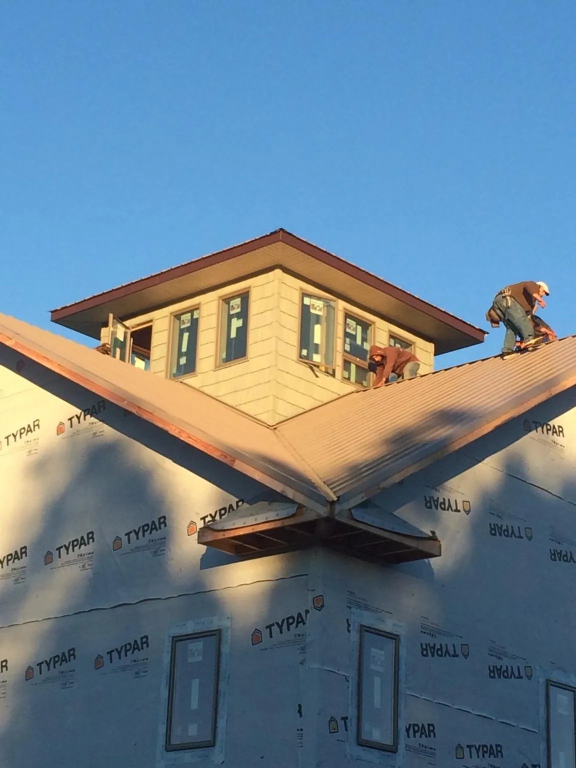 Roofers working around a rooftop cupola on a new metal roof at sunset — Roof Waterproofing in Lupton City by Roofing Brothers